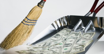 Sweeping US currency into dust pan --- Image by © Steve Hix/Somos Images/Corbis