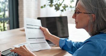 Senior,Mature,Business,Woman,Holding,Paper,Bill,Using,Calculator,,Old