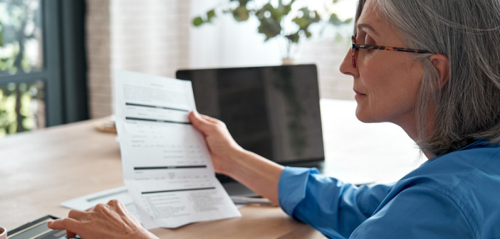 Senior,Mature,Business,Woman,Holding,Paper,Bill,Using,Calculator,,Old