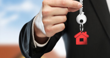 Hand,Handing,Key,On,Cottage,Background