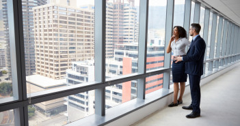 Portrait,Of,New,Business,Owners,By,Empty,Office,Window