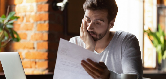 Confused,Frustrated,Young,Man,Reading,Letter,In,Cafe,,Debt,Notification,