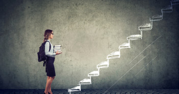 Female,Student,With,Books,Standing,On,The,Stairs,Of,Education