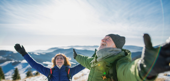 Senior,Couple,Hikers,In,Snow-covered,Winter,Nature,,Stretching,Arms.