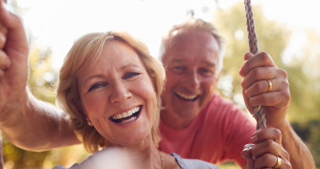 Portrait,Of,Retired,Couple,Having,Fun,With,Man,Pushing,Woman