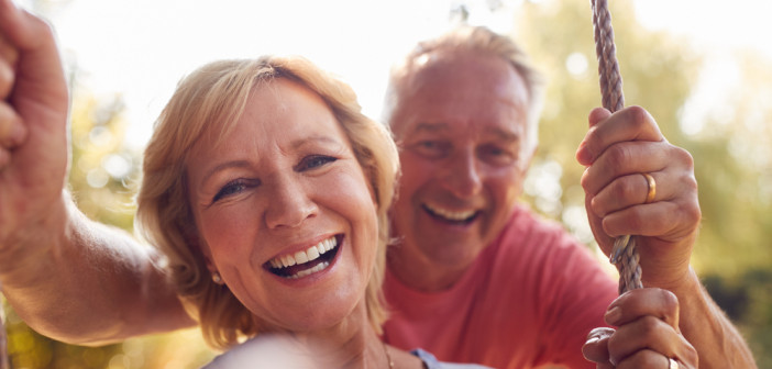 Portrait,Of,Retired,Couple,Having,Fun,With,Man,Pushing,Woman