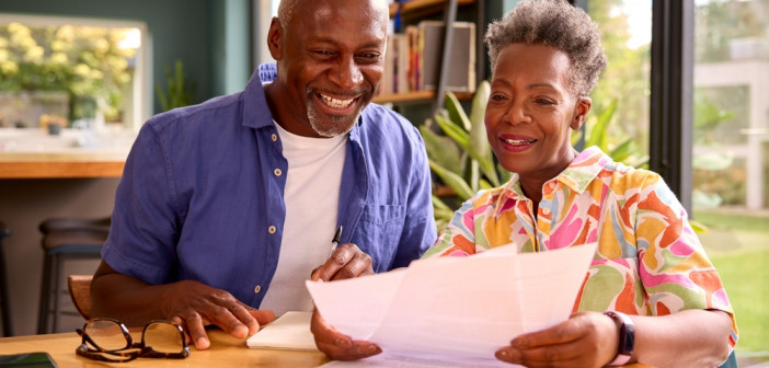 Smiling,Senior,Couple,Sitting,Around,Table,At,Home,Reviewing,Finances