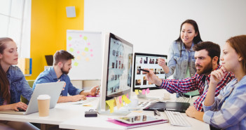 Businessman,Showing,Computer,Screen,To,Coworkers,In,Creative,Office