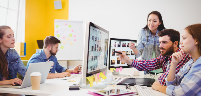 Businessman,Showing,Computer,Screen,To,Coworkers,In,Creative,Office