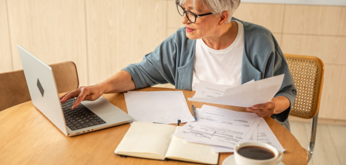 Middle,Aged,Senior,Woman,Sit,With,Laptop,And,Paper,Document,