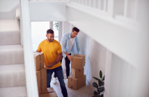 Excited,Male,Couple,Carrying,Boxes,Through,Front,Door,Of,New