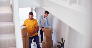 Excited,Male,Couple,Carrying,Boxes,Through,Front,Door,Of,New