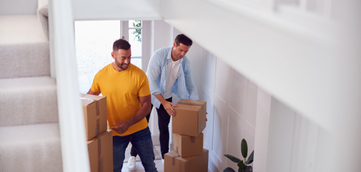 Excited,Male,Couple,Carrying,Boxes,Through,Front,Door,Of,New