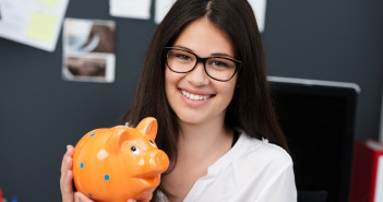 Successful,Young,Businesswoman,Or,Entrepreneur,Holding,A,Piggy,Bank,Looking