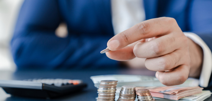 Businessman,Holding,Euro,Cents,Coins,Dollar,Bills,On,Table,With