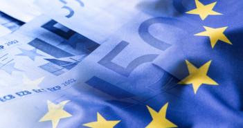 Colorful,Waving,European,Union,Flag,On,A,Euro,Money,Background.