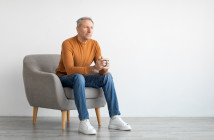 Mature,Man,Drinking,Coffee,Sitting,On,Chair,In,Living,Room.