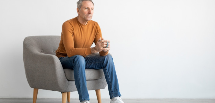 Mature,Man,Drinking,Coffee,Sitting,On,Chair,In,Living,Room.