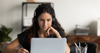 Focused,Female,Adult,Student,In,Headphones,Using,Laptop,,Attending,Online