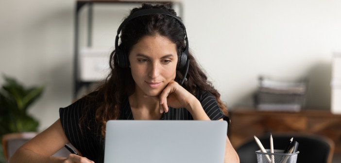 Focused,Female,Adult,Student,In,Headphones,Using,Laptop,,Attending,Online