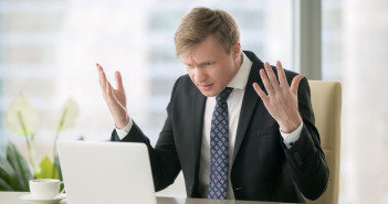 Young,Stressed,Handsome,Businessman,Working,At,Desk,In,Modern,Office