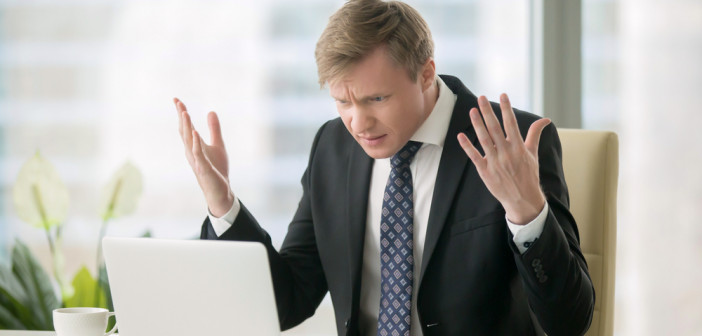 Young,Stressed,Handsome,Businessman,Working,At,Desk,In,Modern,Office