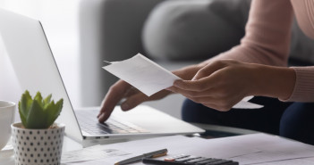 Close,Up,Woman,Holding,Receipt,,Using,Laptop,,Calculating,Bills,,Money,
