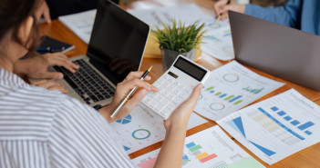 Businesswoman,Using,A,Calculator,To,Calculate,Numbers,On,A,Company's