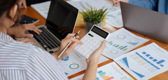 Businesswoman,Using,A,Calculator,To,Calculate,Numbers,On,A,Company's